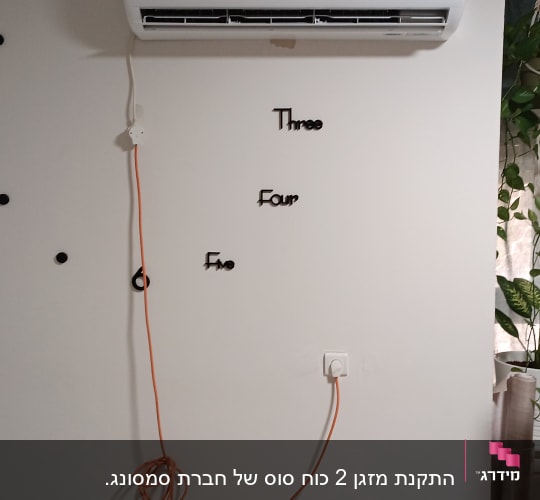 מזגן מותקן על קיר עם כבל חשמל כתום